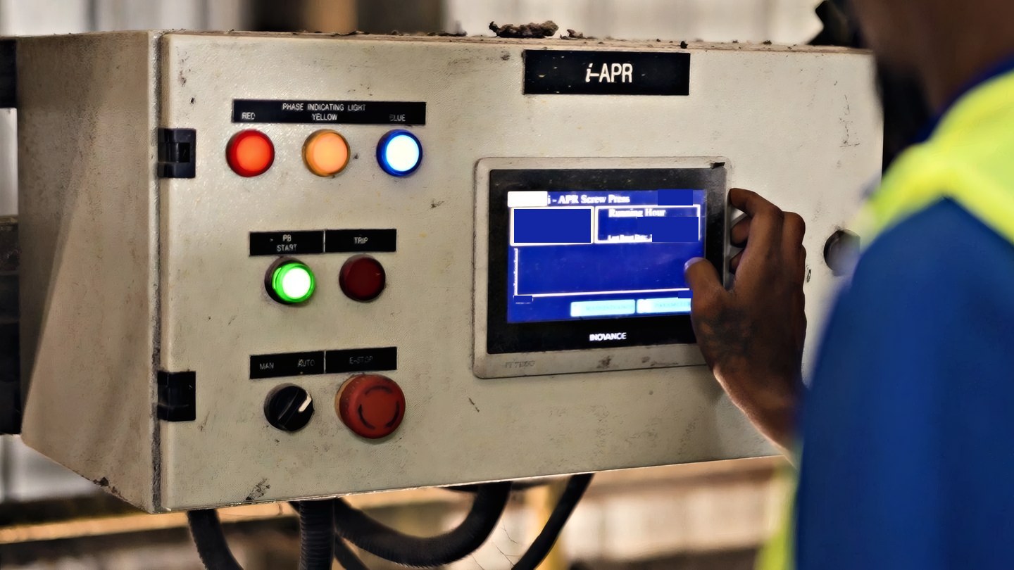 The i-APR control panel on the mill floor at Minsawi Industries, its indicator lamps lit and a hand at the touchscreen. A frame from AIREI’s own footage of the installation.