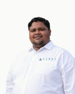 Potret studio di atas latar putih suam yang rata: seorang lelaki muda tersenyum dengan mata mengecil, memakai kemeja putih lengan panjang berpoket dada dengan logo AIREI biru kecil di atasnya. Tona kemejanya hampir sama dengan latar, jadi garis luarnya kelihatan samar.